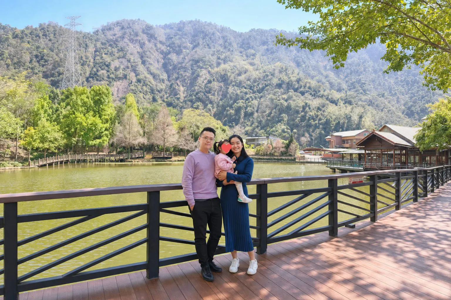 Xander and Zane with a child beside a lake, the child’s face covered by a heart